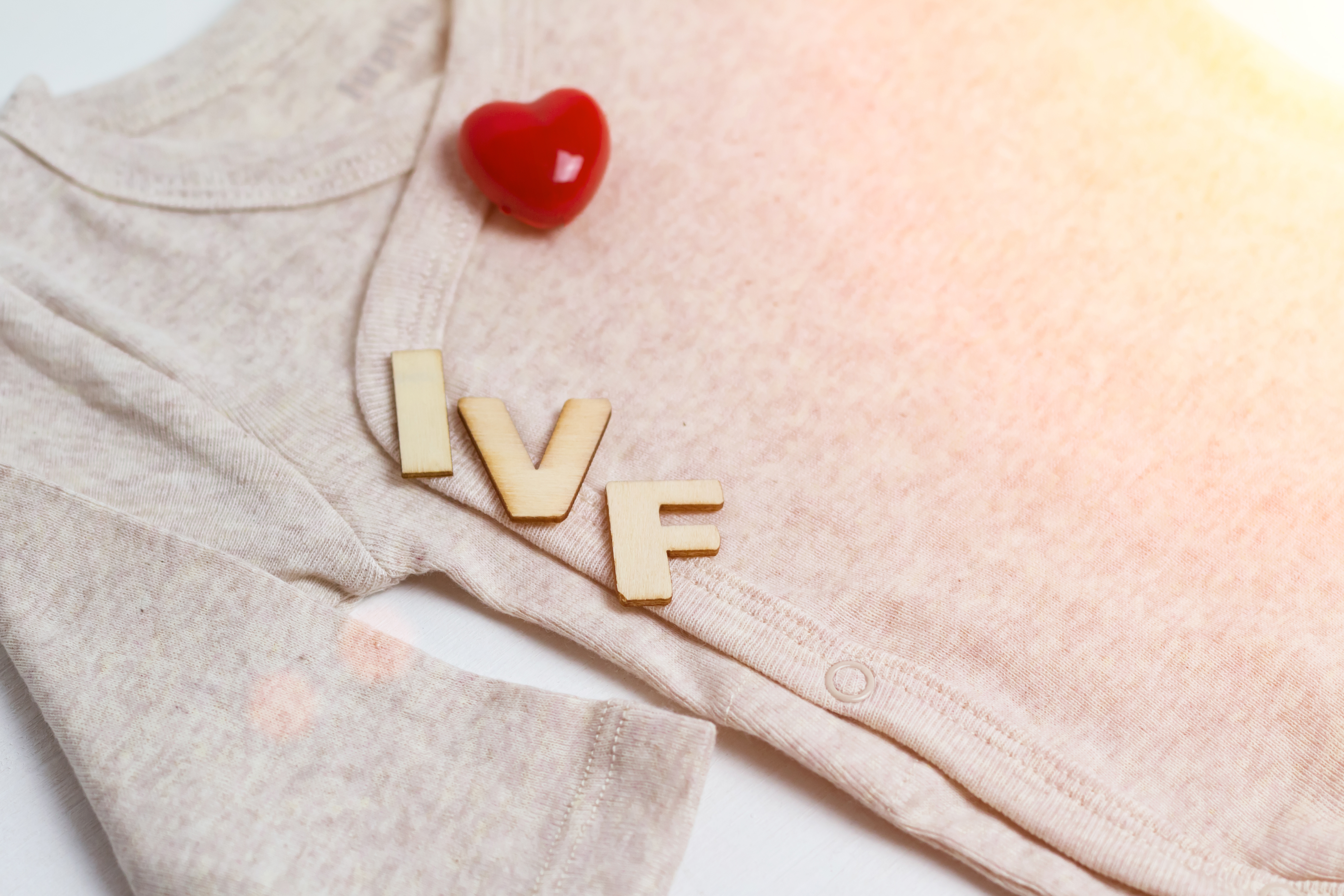 Baby grow with IVF letters and a red heart